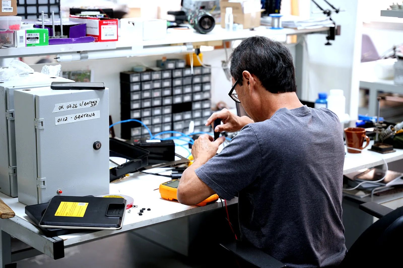 Técnico trabalhando em componente eletrônico na bancada do laboratório.